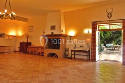 Terrasse ensoleillée avec tables et chaises en bois, entourée de verdure et d'une façade recouverte de lierre.