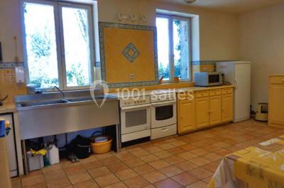 Terrasse ensoleillée avec tables et chaises en bois, entourée de verdure et d'une façade recouverte de lierre.