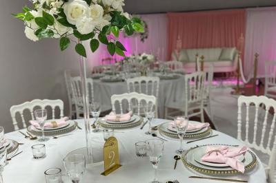 Canapé blanc devant un rideau rose, entouré de bougeoirs dorés en forme de cages et d'une table en verre.