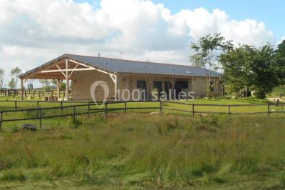 Chambre avec lit double, tête de lit en bois, bureau, chaise, robe blanche sur un mannequin et tableau coloré au mur.