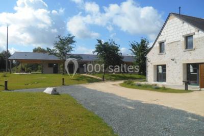 Chambre avec lit double, tête de lit en bois, bureau, chaise, robe blanche sur un mannequin et tableau coloré au mur.