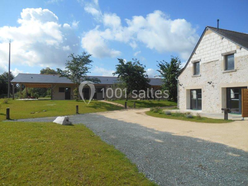 Bâtiments en pierre et modernes entourés de pelouses et d'arbres sous un ciel partiellement nuageux.