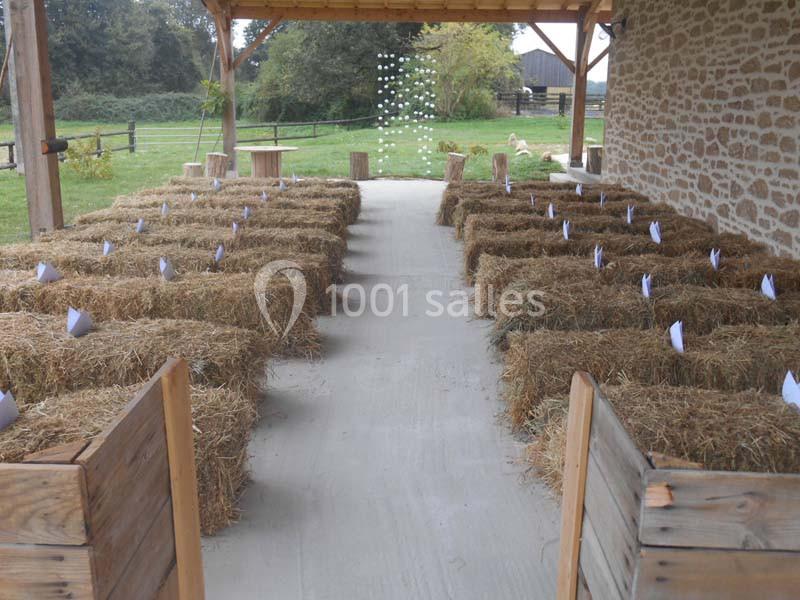 Bottes de paille disposées en rangées sous un abri en bois, formant un espace de type assise en extérieur.