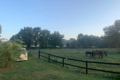 Chambre avec lit double, tête de lit en bois, bureau, chaise, robe blanche sur un mannequin et tableau coloré au mur.