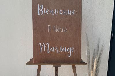 Chambre avec lit double, tête de lit en bois, bureau, chaise, robe blanche sur un mannequin et tableau coloré au mur.