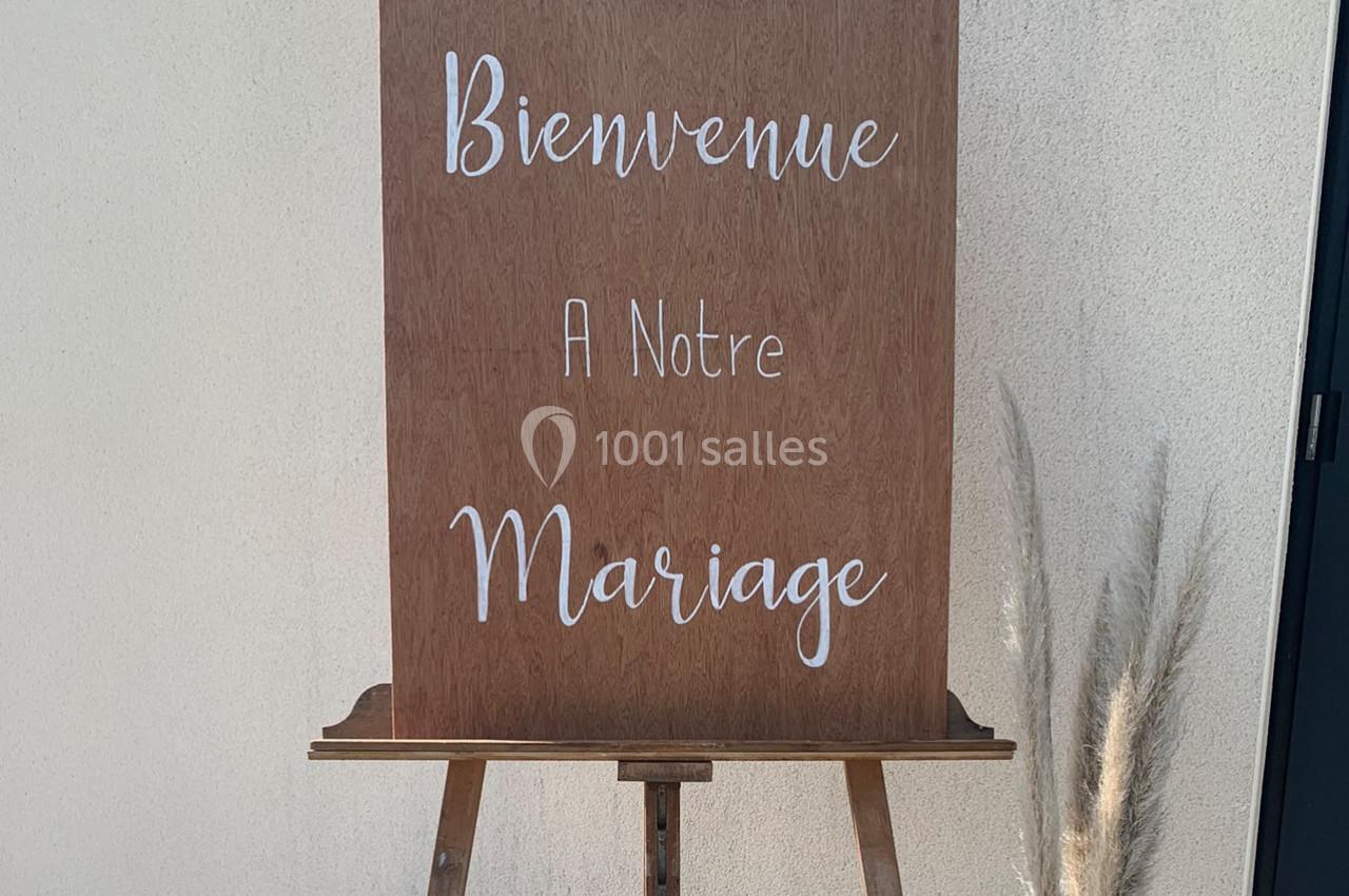 Panneau en bois sur un chevalet avec l'inscription ’Bienvenue à notre mariage’, décoré de pampas à droite.