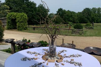 Chambre avec lit double, tête de lit en bois, bureau, chaise, robe blanche sur un mannequin et tableau coloré au mur.