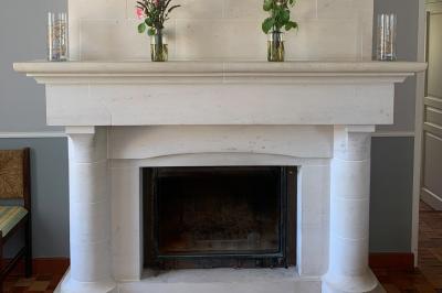 Chambre avec lit double, tête de lit en bois, bureau, chaise, robe blanche sur un mannequin et tableau coloré au mur.
