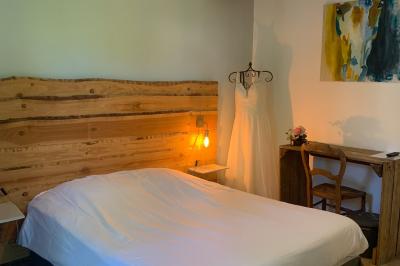 Chambre avec lit double, tête de lit en bois, bureau, chaise, robe blanche sur un mannequin et tableau coloré au mur.