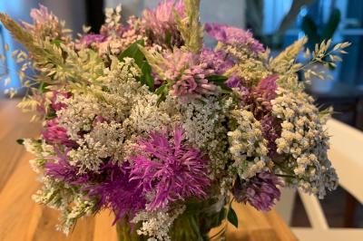 Chambre avec lit double, tête de lit en bois, bureau, chaise, robe blanche sur un mannequin et tableau coloré au mur.