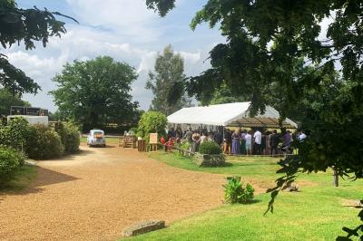 Chambre avec lit double, tête de lit en bois, bureau, chaise, robe blanche sur un mannequin et tableau coloré au mur.