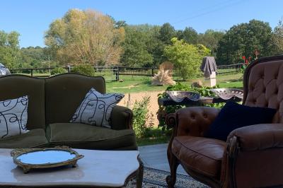 Chambre avec lit double, tête de lit en bois, bureau, chaise, robe blanche sur un mannequin et tableau coloré au mur.