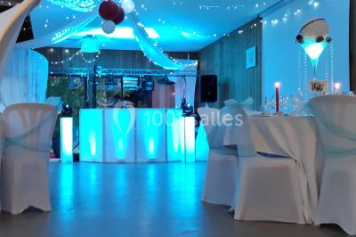 Structure en bois avec bancs alignés pour un événement, décorée de fleurs, avec un manoir en arrière-plan.