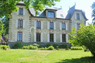 Structure en bois avec bancs alignés pour un événement, décorée de fleurs, avec un manoir en arrière-plan.