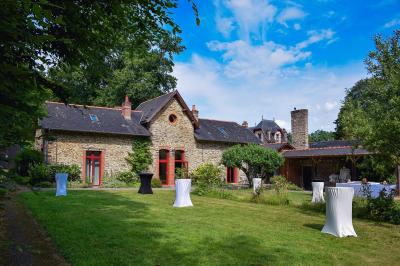 Structure en bois avec bancs alignés pour un événement, décorée de fleurs, avec un manoir en arrière-plan.