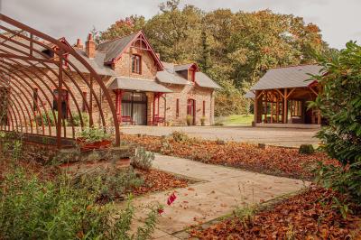 Structure en bois avec bancs alignés pour un événement, décorée de fleurs, avec un manoir en arrière-plan.