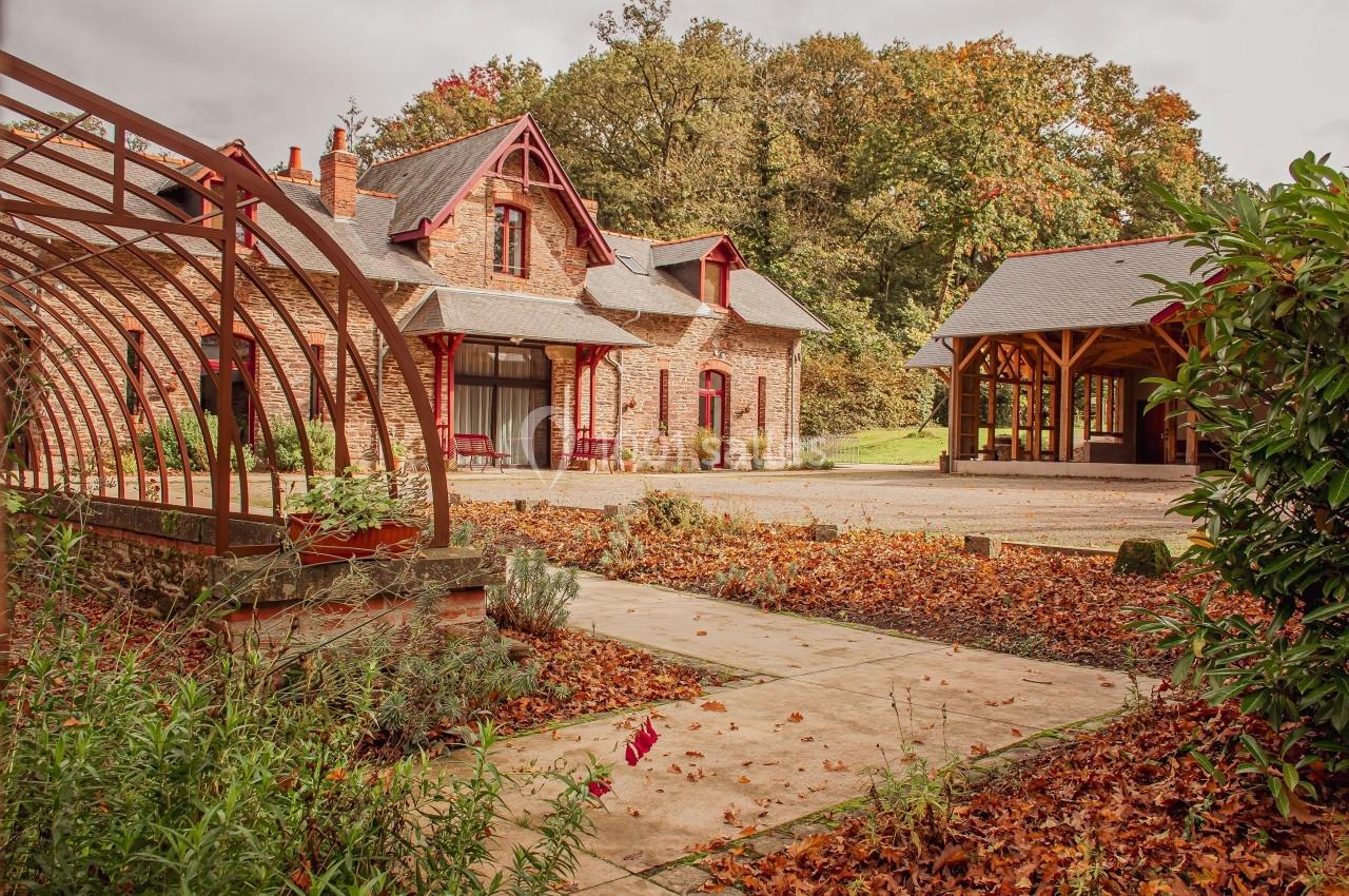 Bâtiments en pierre avec toit en ardoise entourés de végétation automnale et d'une structure métallique.