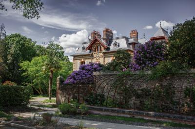Structure en bois avec bancs alignés pour un événement, décorée de fleurs, avec un manoir en arrière-plan.