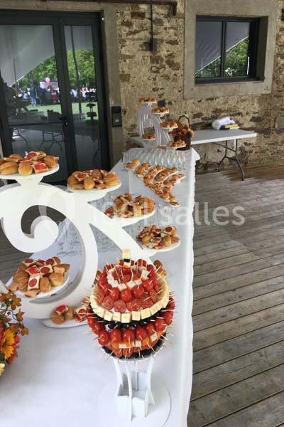 Buffet de réception avec divers amuse-bouches et brochettes disposés sur une table décorative en extérieur.