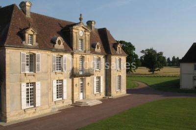 Grand espace vert avec des tentes blanches installées sur une pelouse, entouré d'arbres et d'un ciel partiellement nuageux.