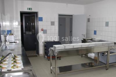 Cuisine professionnelle avec plans de travail en inox, assiettes alignées, et plats préparés sur un évier.