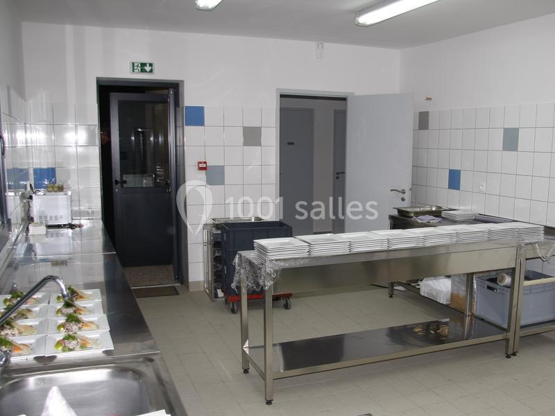 Cuisine professionnelle avec plans de travail en inox, assiettes alignées, et plats préparés sur un évier.