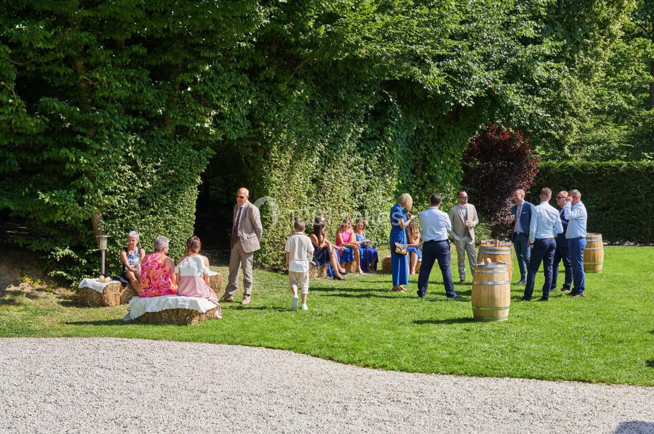 Groupe de personnes discutant et assises dans un jardin verdoyant par une journée ensoleillée.