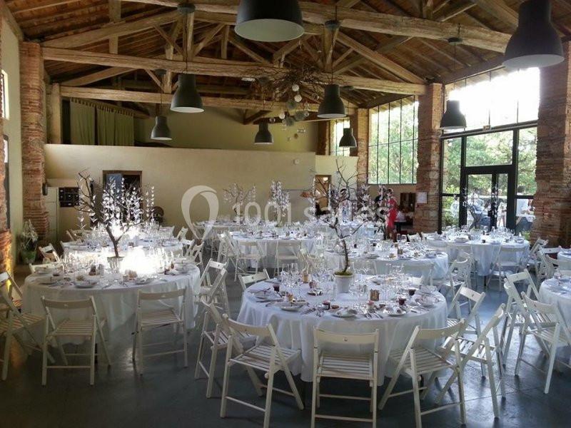 Salle de réception lumineuse avec tables rondes décorées de nappes blanches et centres de table élégants.