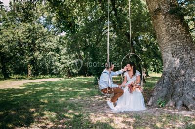 Un couple regarde un feu d'artifice illuminant le ciel nocturne, entouré d'arbres sombres.