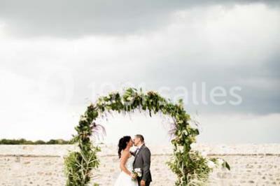 Canapé gris avec coussins, table basse avec magazines et télécommande, tableau mural et fenêtre laissant entrer la lumière.