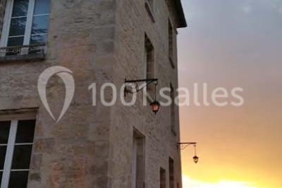 Canapé gris avec coussins, table basse avec magazines et télécommande, tableau mural et fenêtre laissant entrer la lumière.