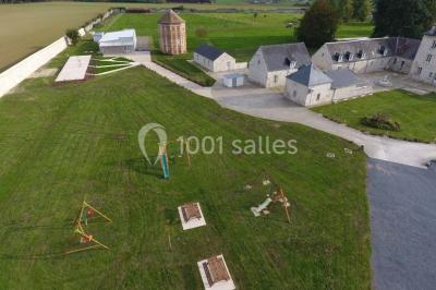 Canapé gris avec coussins, table basse avec magazines et télécommande, tableau mural et fenêtre laissant entrer la lumière.