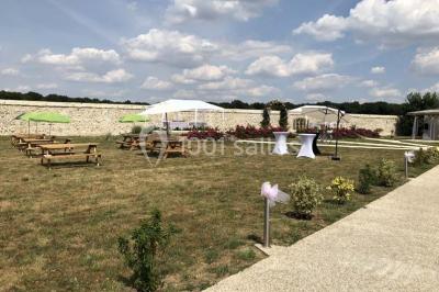 Canapé gris avec coussins, table basse avec magazines et télécommande, tableau mural et fenêtre laissant entrer la lumière.