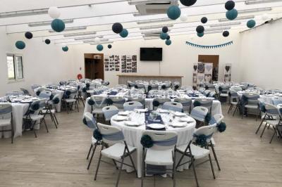 Canapé gris avec coussins, table basse avec magazines et télécommande, tableau mural et fenêtre laissant entrer la lumière.