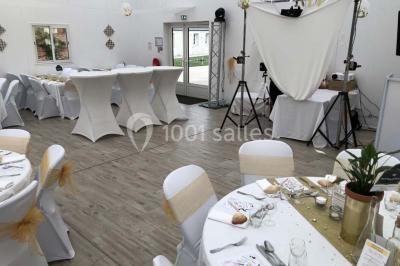 Canapé gris avec coussins, table basse avec magazines et télécommande, tableau mural et fenêtre laissant entrer la lumière.