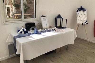 Canapé gris avec coussins, table basse avec magazines et télécommande, tableau mural et fenêtre laissant entrer la lumière.