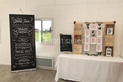 Canapé gris avec coussins, table basse avec magazines et télécommande, tableau mural et fenêtre laissant entrer la lumière.