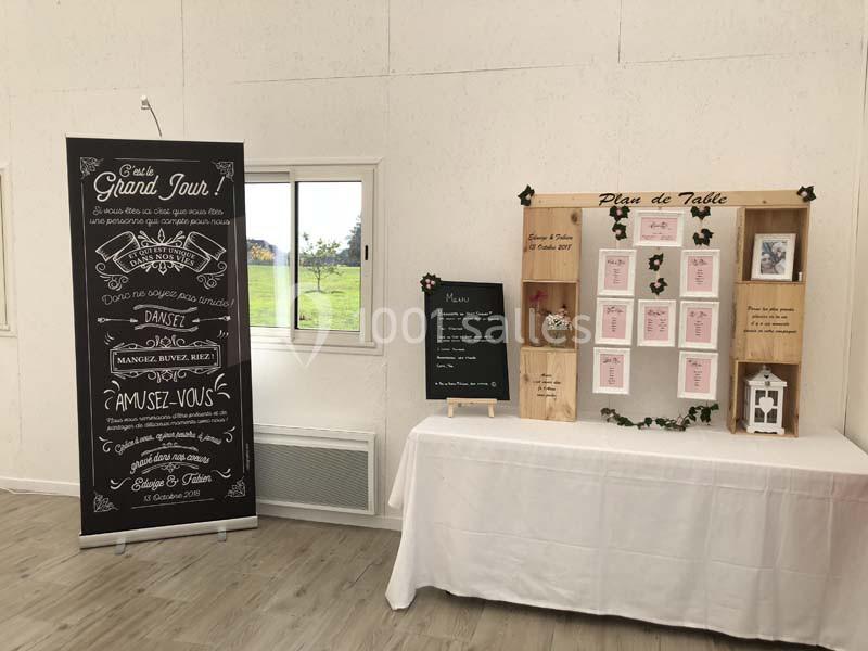 Décoration de mariage avec panneau d'accueil, tableau de menu, plan de table et éléments décoratifs sur une table.