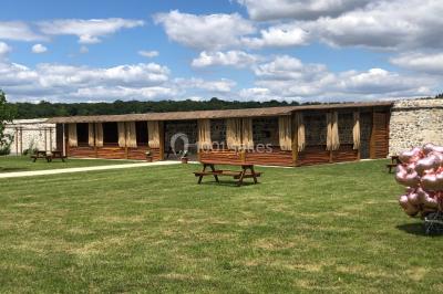 Canapé gris avec coussins, table basse avec magazines et télécommande, tableau mural et fenêtre laissant entrer la lumière.