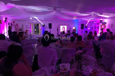 Canapé gris avec coussins, table basse avec magazines et télécommande, tableau mural et fenêtre laissant entrer la lumière.