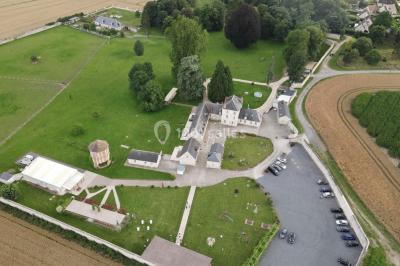 Canapé gris avec coussins, table basse avec magazines et télécommande, tableau mural et fenêtre laissant entrer la lumière.