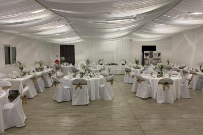 Canapé gris avec coussins, table basse avec magazines et télécommande, tableau mural et fenêtre laissant entrer la lumière.