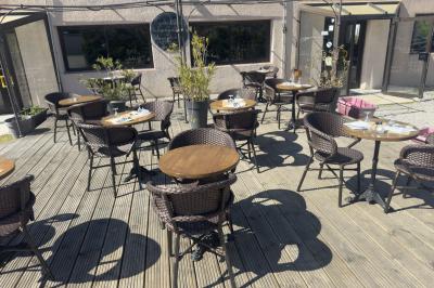 Salle de réception décorée avec des tables rondes dressées, nappes blanches, chaises blanches et touches de rose.