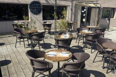 Salle de réception décorée avec des tables rondes dressées, nappes blanches, chaises blanches et touches de rose.