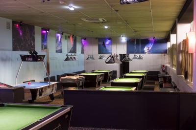 Salle de bowling avec plusieurs pistes, boules colorées au premier plan et décorations murales en bois et surf.