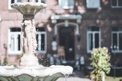 Salle de réception lumineuse avec tables dressées, lustres suspendus et nappes blanches sur des tables latérales.