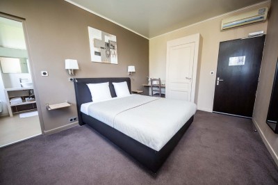 Salle de réception lumineuse avec tables dressées, lustres suspendus et nappes blanches sur des tables latérales.