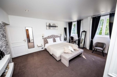 Salle de réception lumineuse avec tables dressées, lustres suspendus et nappes blanches sur des tables latérales.