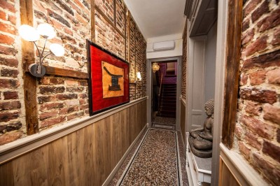 Salle de réception lumineuse avec tables dressées, lustres suspendus et nappes blanches sur des tables latérales.