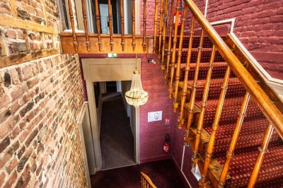 Salle de réception lumineuse avec tables dressées, lustres suspendus et nappes blanches sur des tables latérales.